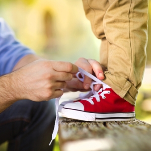 man tying child's shoes